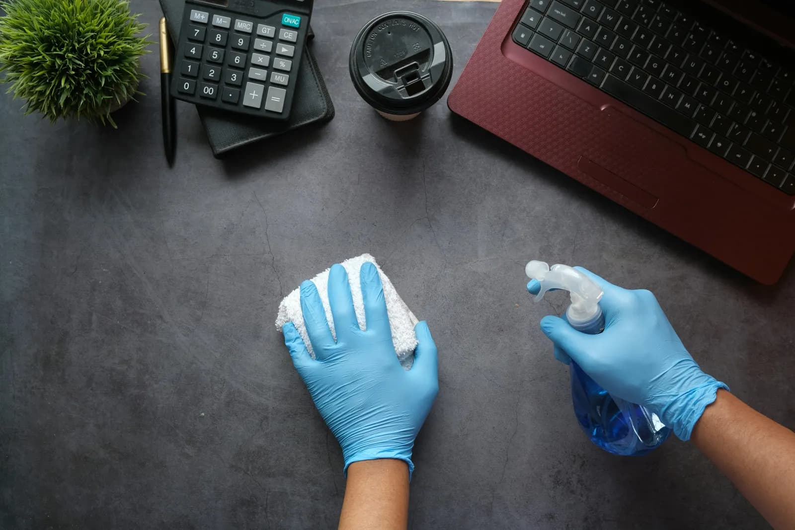 Desinfektion eines Schreibtischs im Büro mit Handschuhen